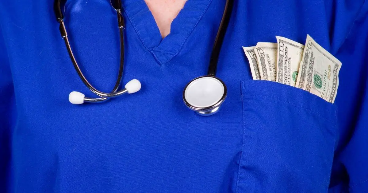 A person wearing a blue medical scrub top with a stethoscope around their neck and a wad of US dollar bills, representing their CNA salary, in their pocket.